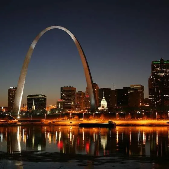 The St. Louis Gateway Arch at night, with the city skyline in the background.