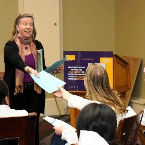 A speaker distributes handouts to audience members at a conference.