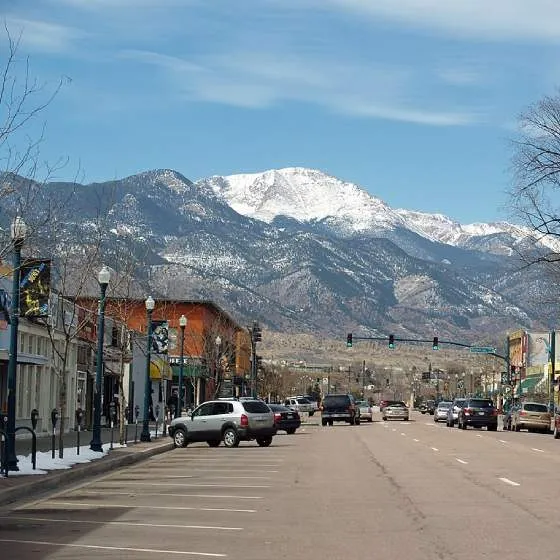 A street through Colorado Springs' business district, with the Rocky Mountains in the background.