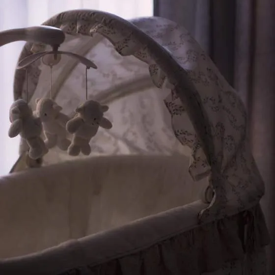 A baby's crib, with rotating toys above the crib.