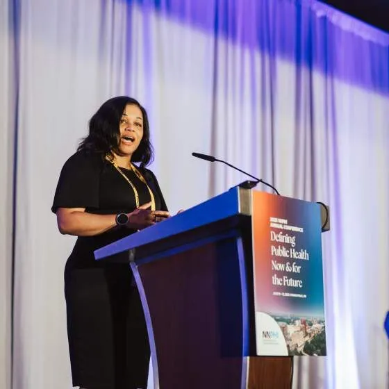 A 2025 NNPHI award winner speaks at a podium at the NNPHI Annual Conference.