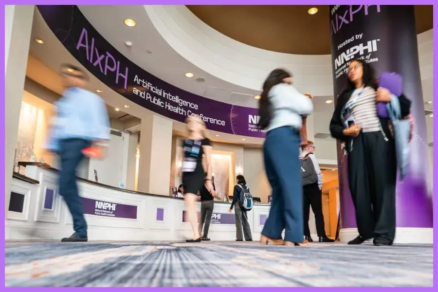 Attendees walk by the registration booth at the AIxPH conference.