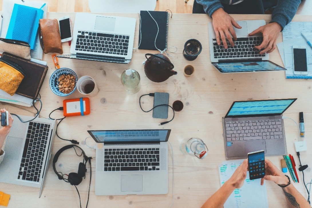 An image of people working on laptops and mobile devices